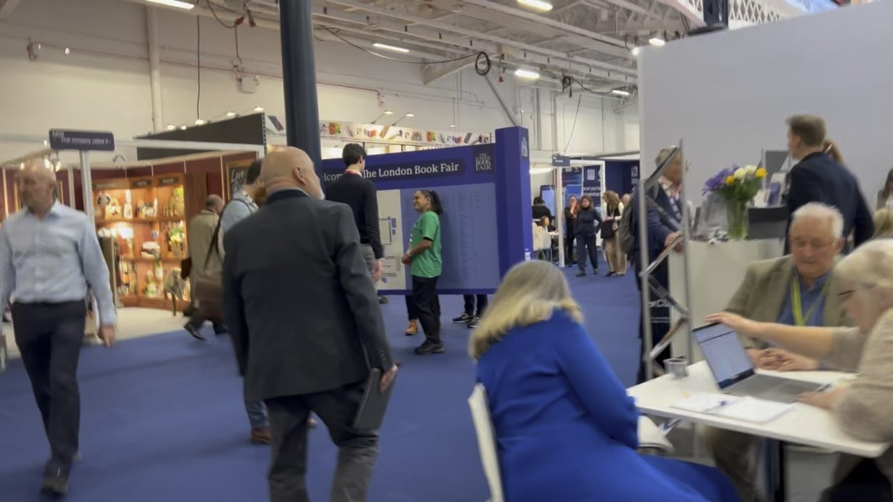 People walking the aisle between stands at the London Book Fair
