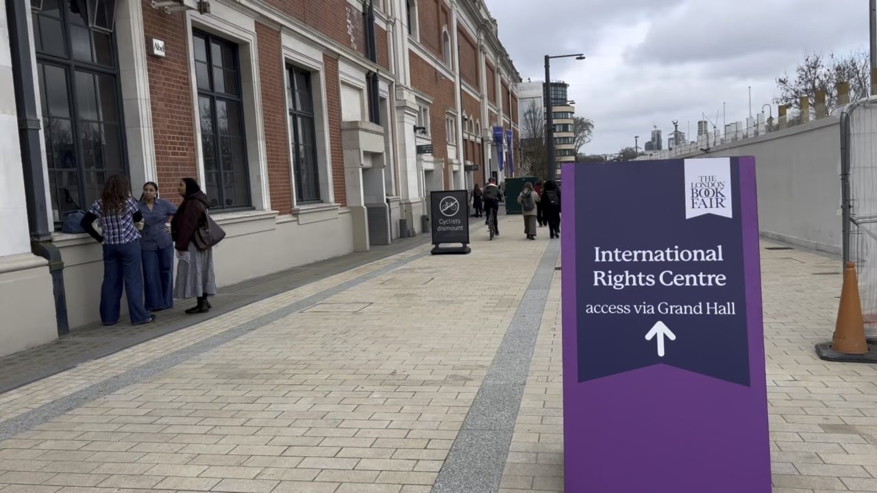 A purple street sign outside Olympia reading International Rights Centre, access via Grand Hall, The London Book Fair